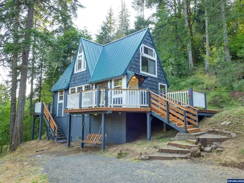 Blue A-frame cabin with a wraparound deck in the woods
